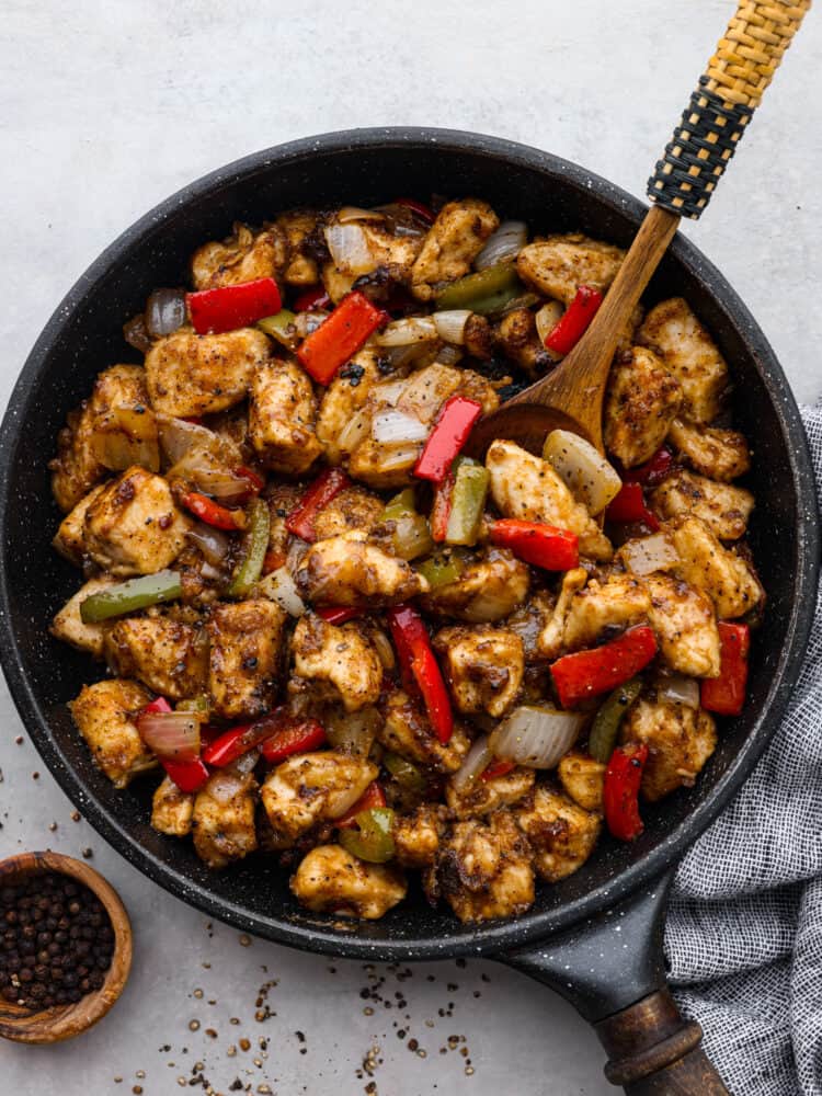 Top-down view of black pepper chicken in a black skillet.