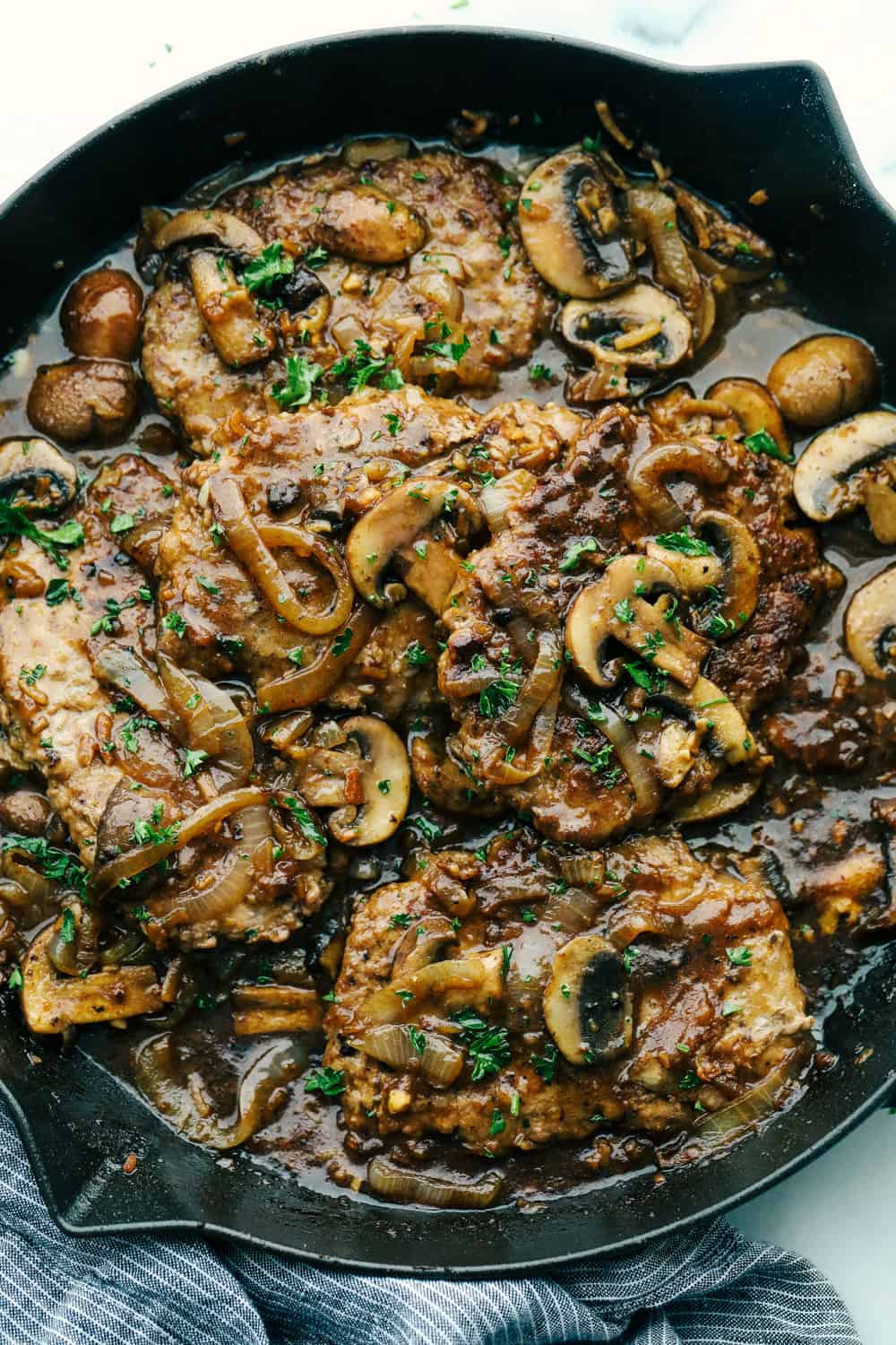 Cube steak cooked in a mushroom gravy sitting in a skillet.