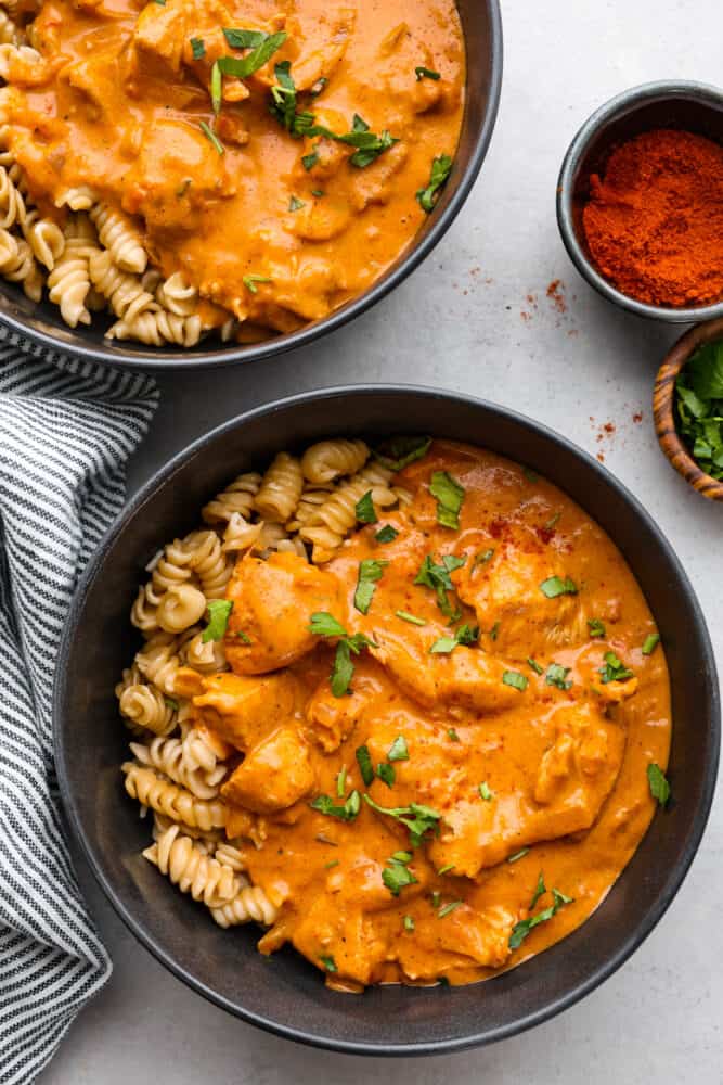 The top view of 2 bowls filled with noodles and chicken paprikash. 