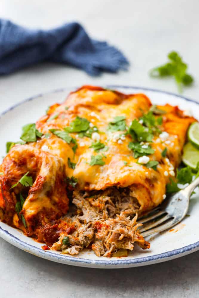 Closeup of pork enchiladas with a bite taken out of them.