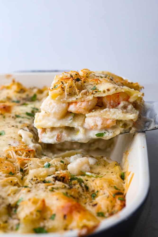 Side view of a slice of the seafood lasagna being lifting out of the pan with a spatula.