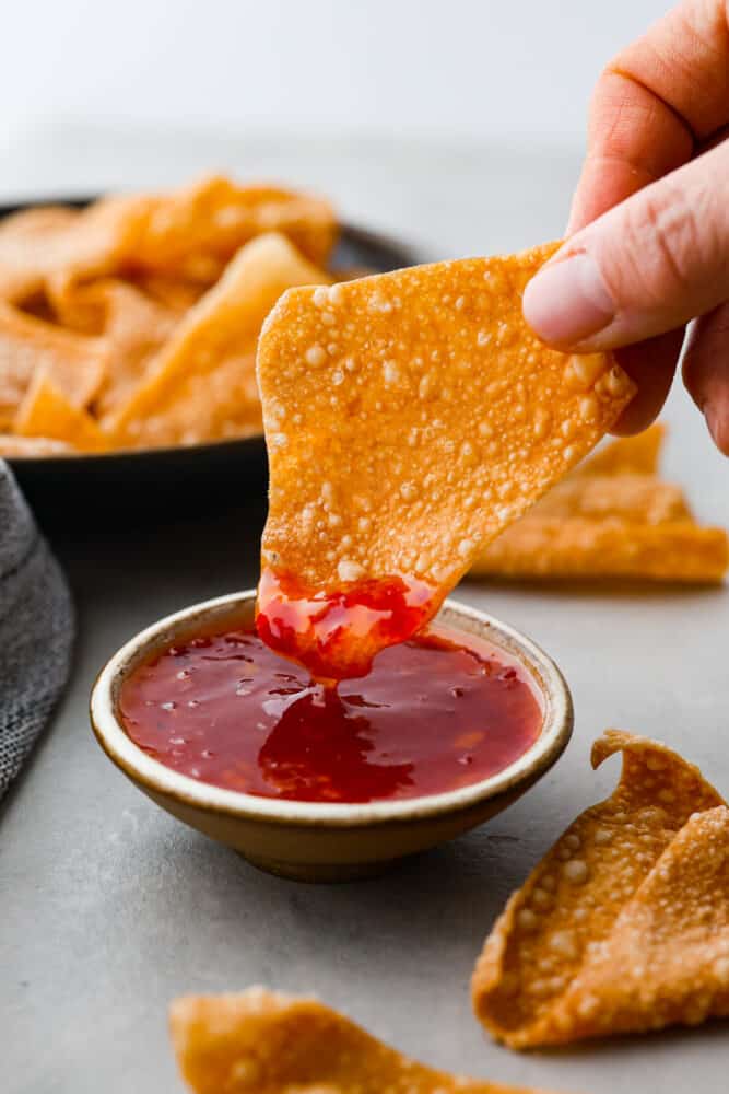 Dipping a chip into sweet and sour sauce.