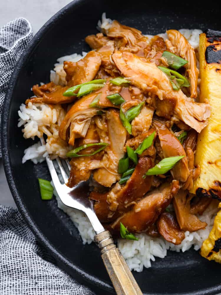 Closeup of huli huli chicken on a black plate.