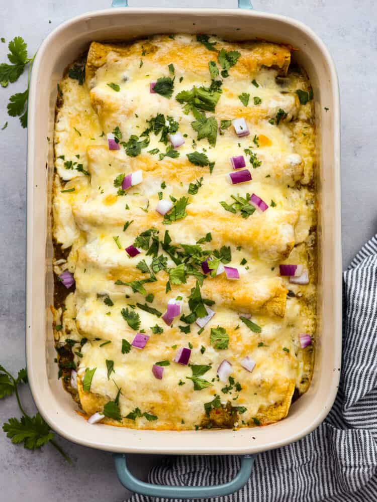 Top-down view of enchiladas suizas in a baking dish.