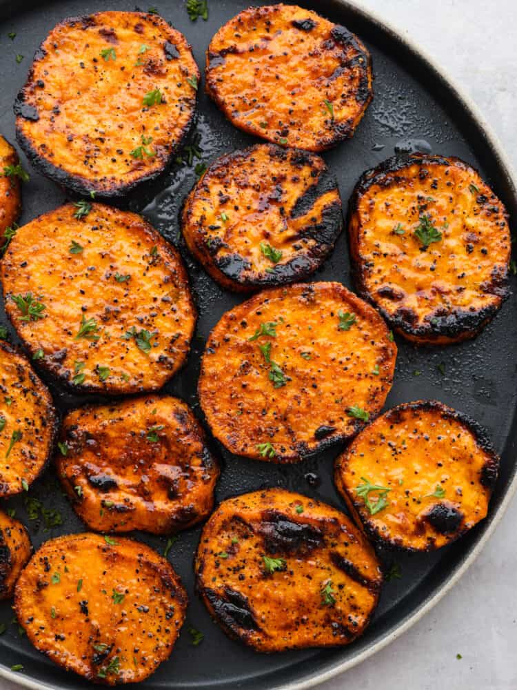 Grilled sweet potato slices served on a black plate.