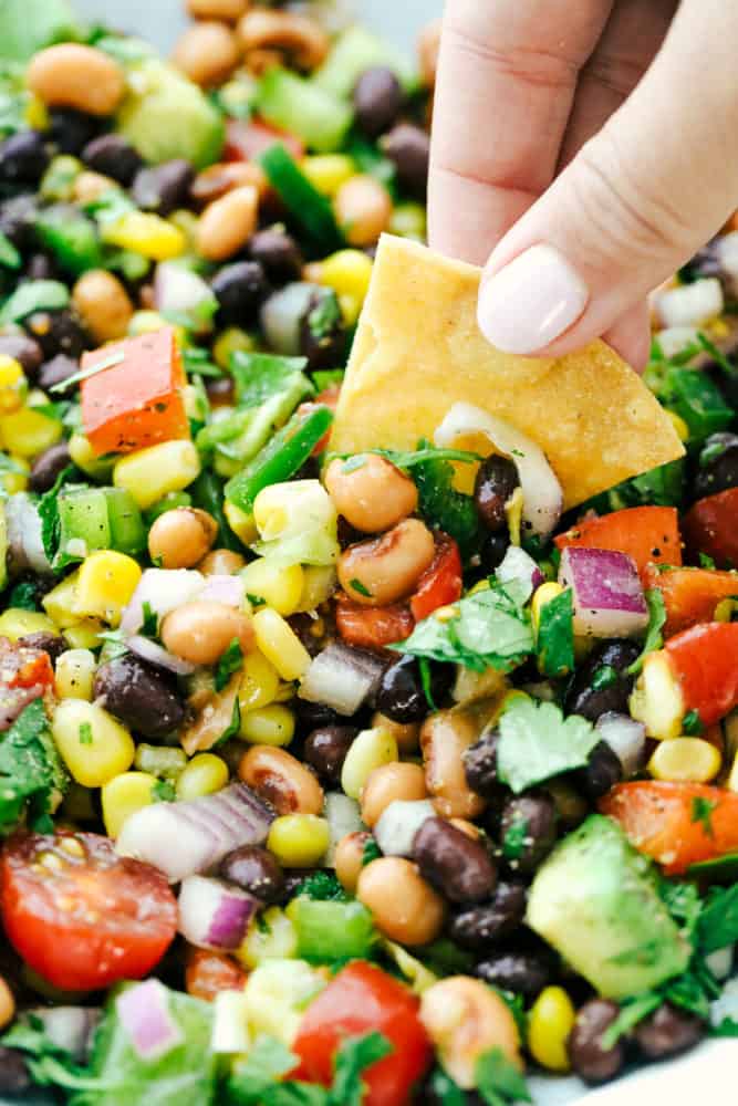 An unclose photo of the caviar and a person dipping in the salsa with a thick, crunchy chip. 