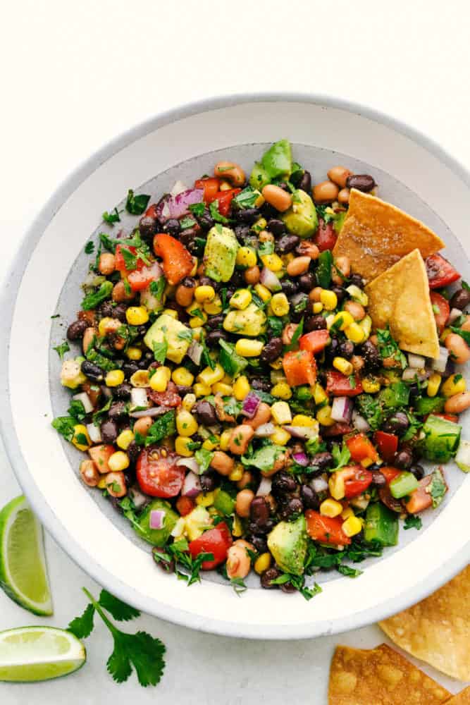 Cowboy caviar in a white bowl with two chips sticking out of the dip. 