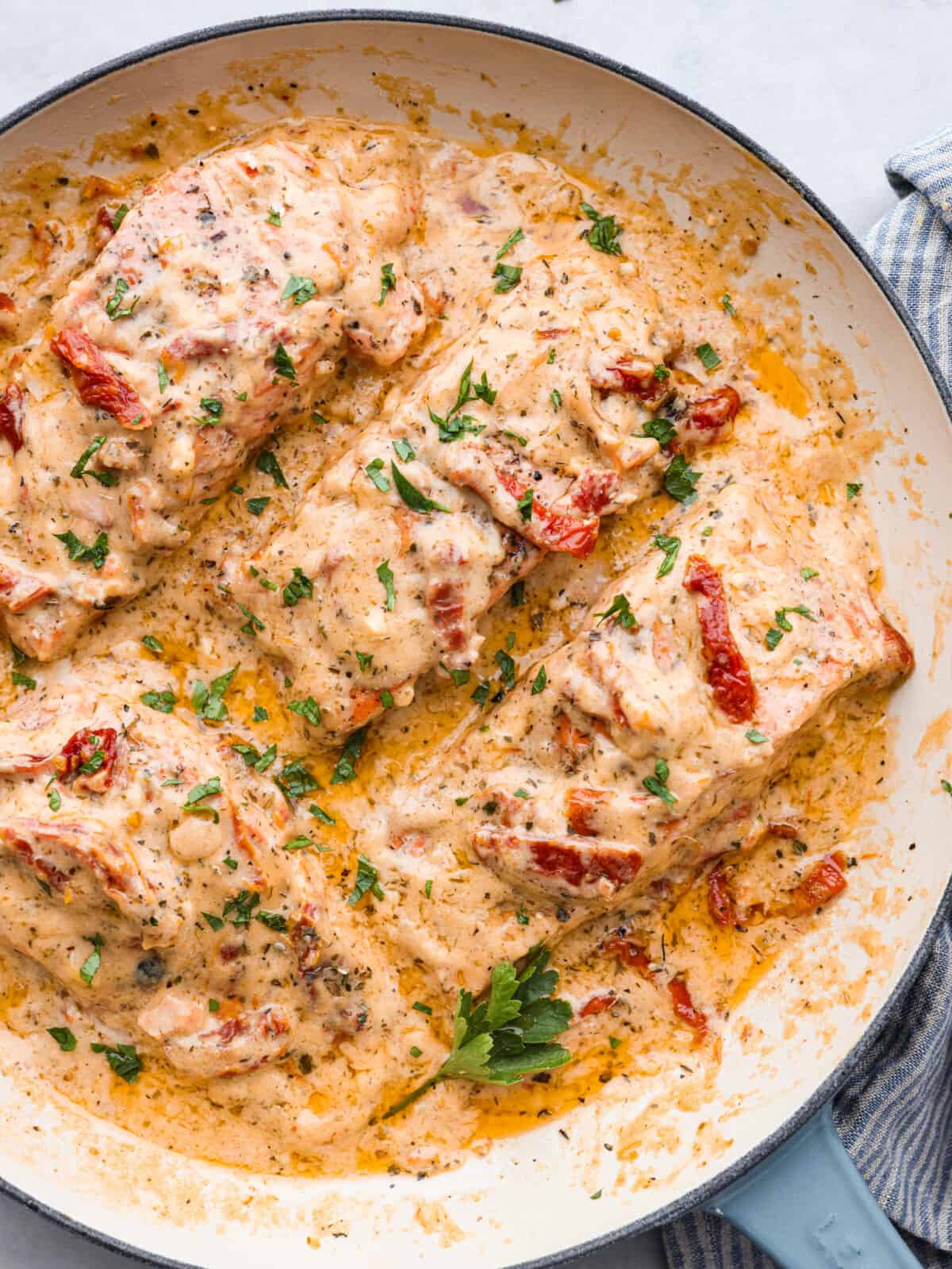 Top-down view of marry me salmon in a white and blue skillet.