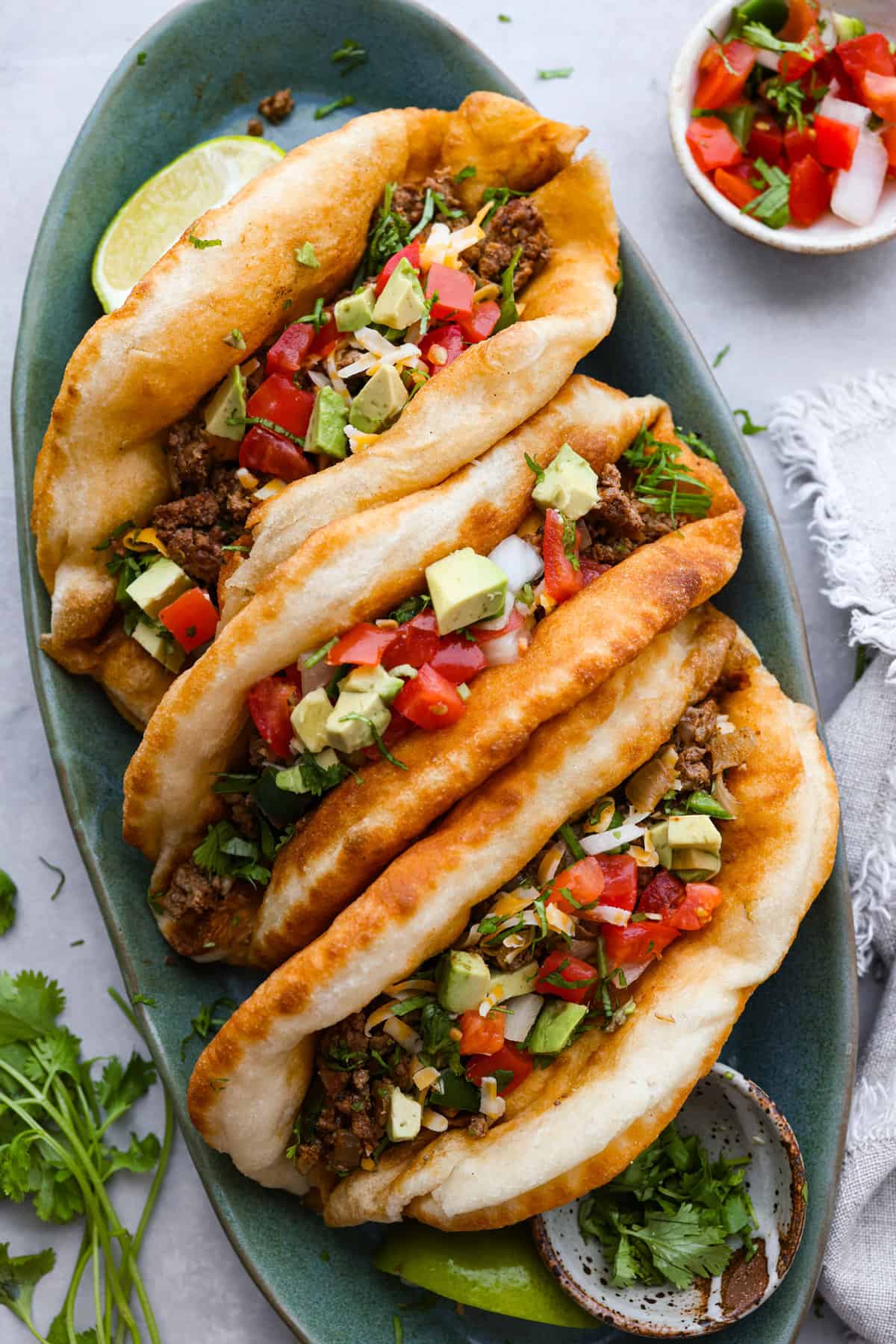 3 chalupas on a blue-green serving platter.