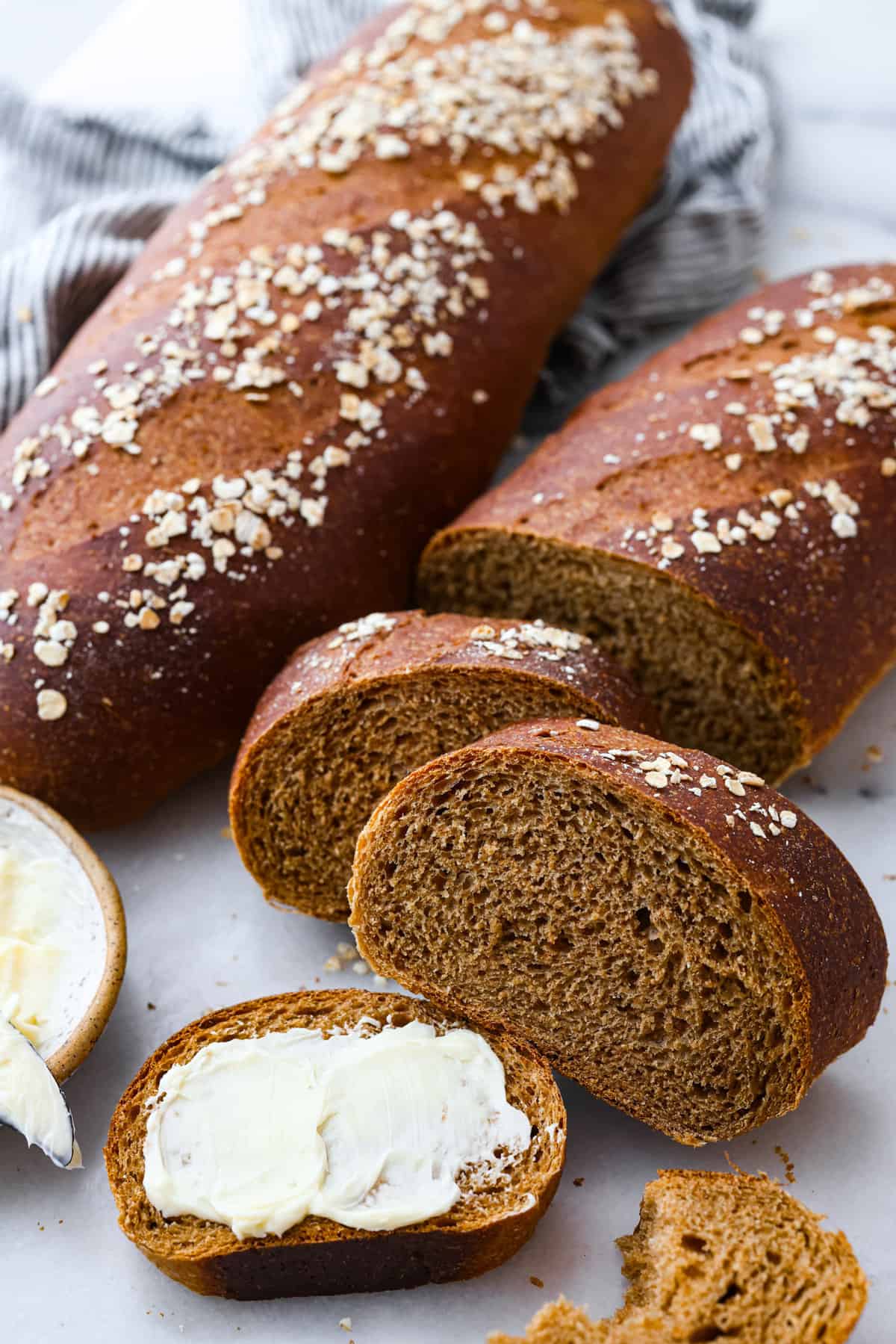 Close view of baked brown bread loves. Once loaf is sliced with butter spread onto a piece of bread.