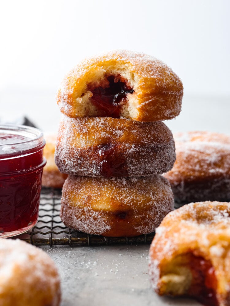 A stack of 3 strawberry filled donuts.