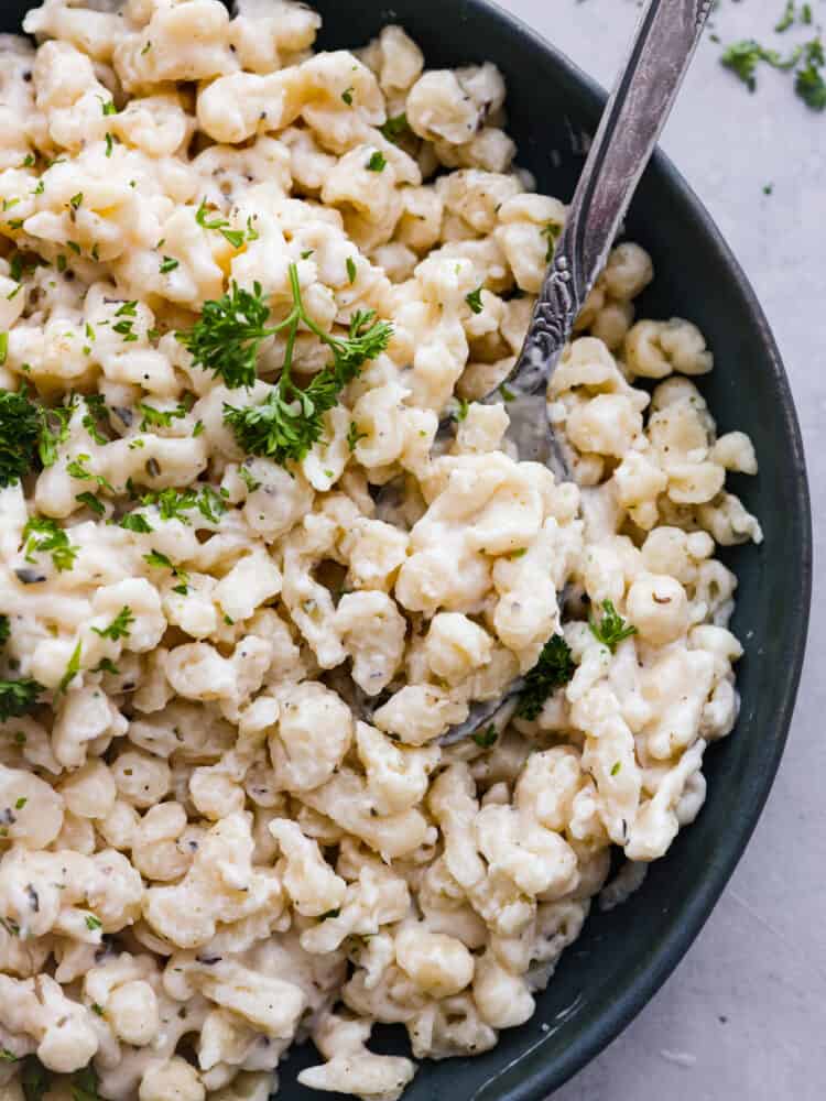 Top-down view of a bowl of spaetzle with a spoon in it.