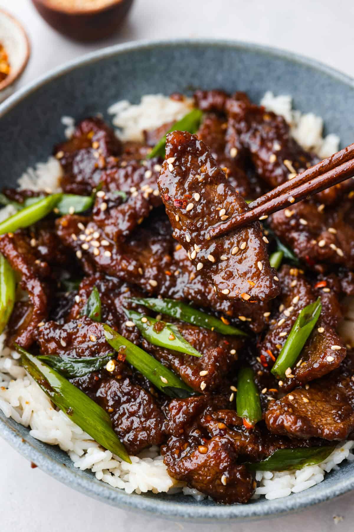 Picking up a piece of Mongolian beef with chopsticks.