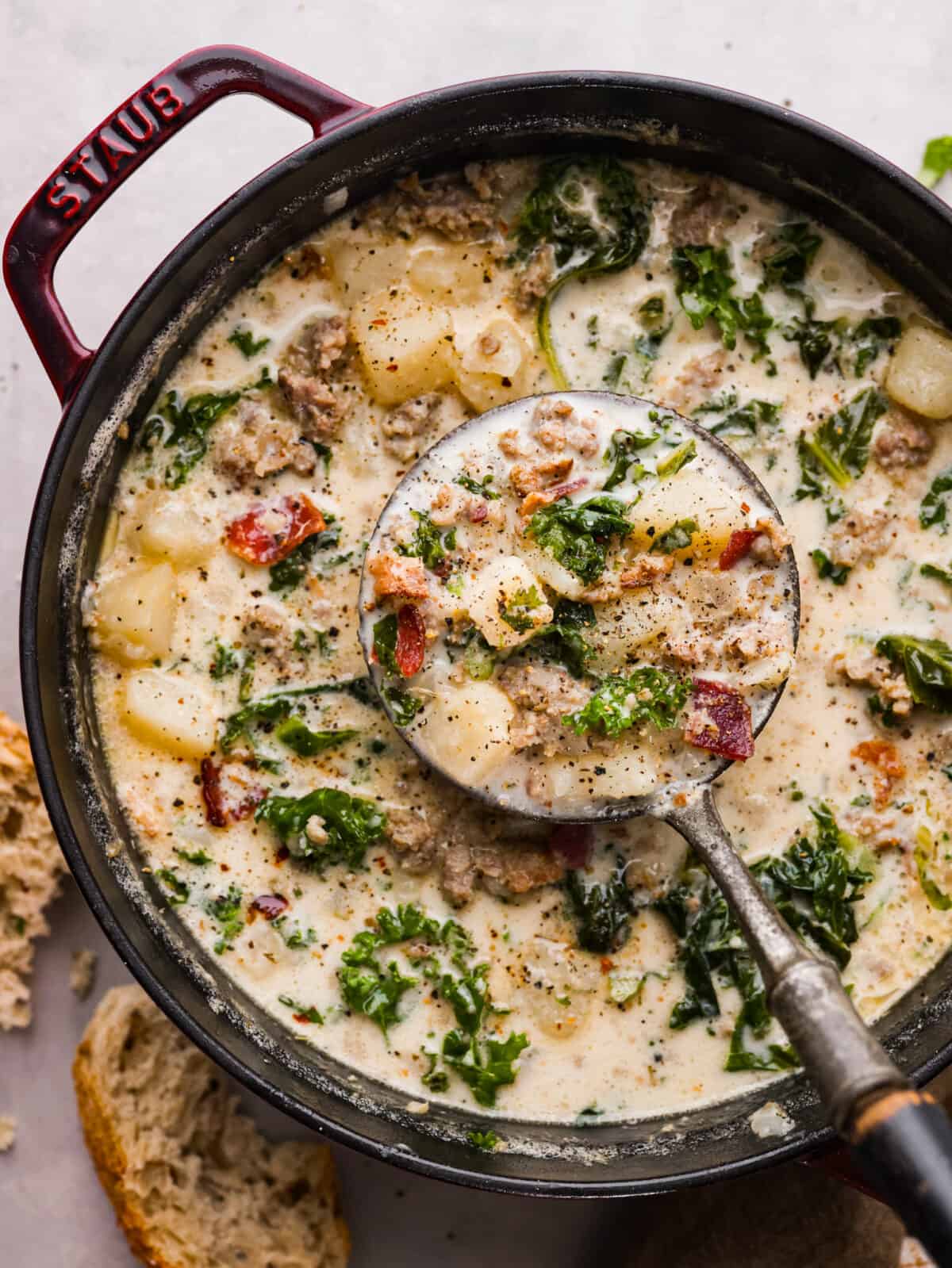 The top view of Zuppa Toscana soup in a pot with a ladle scooping some out. 