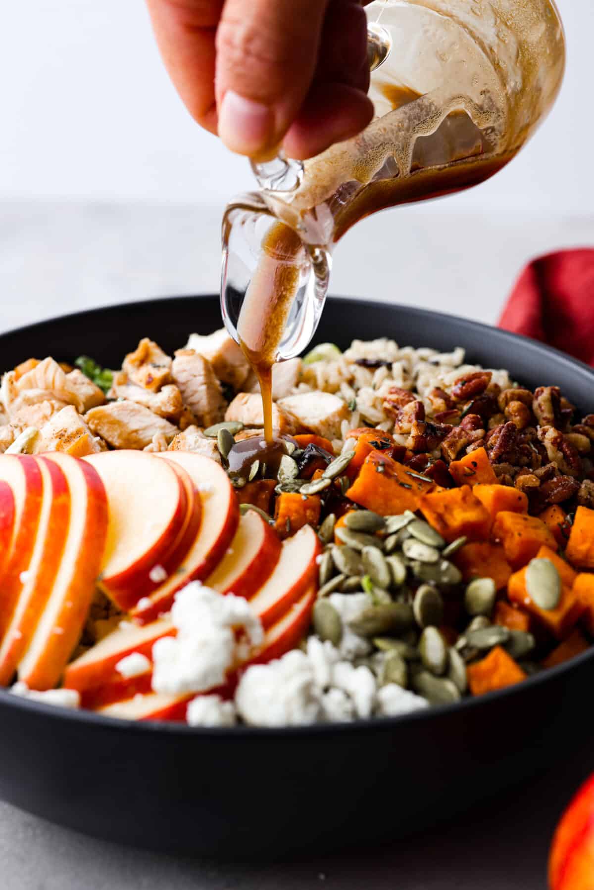 Pouring dressing over a harvest bowl.