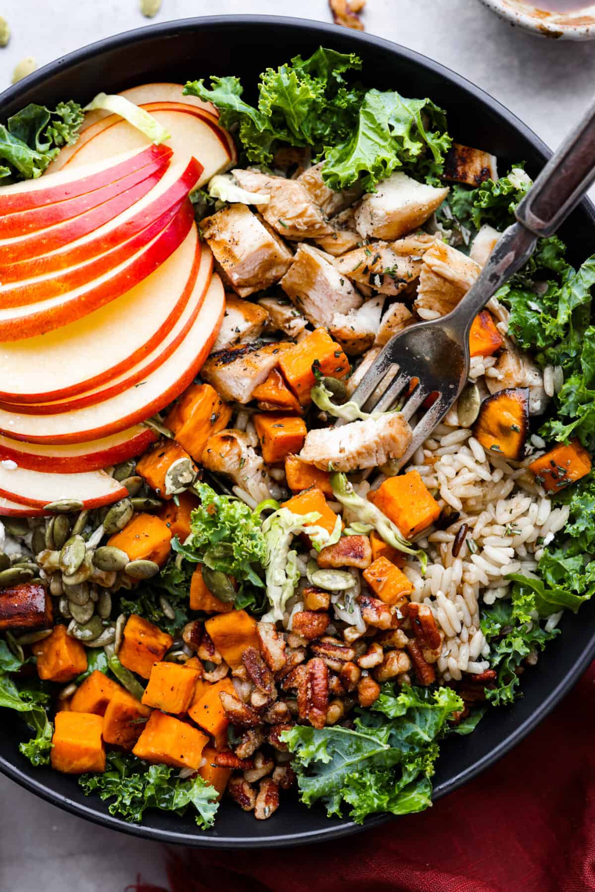 Taking a bite of chicken, greens, sweet potatoes, and rice with a metal fork.