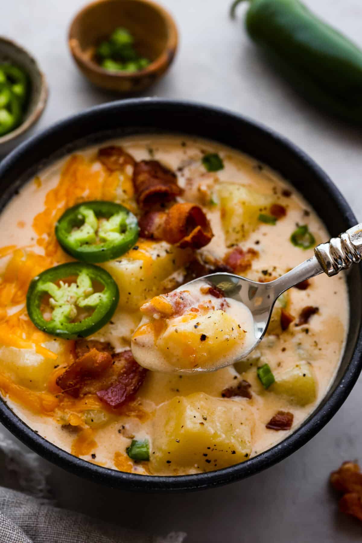 Closeup of a serving of jalapeno popper soup in a black bowl.