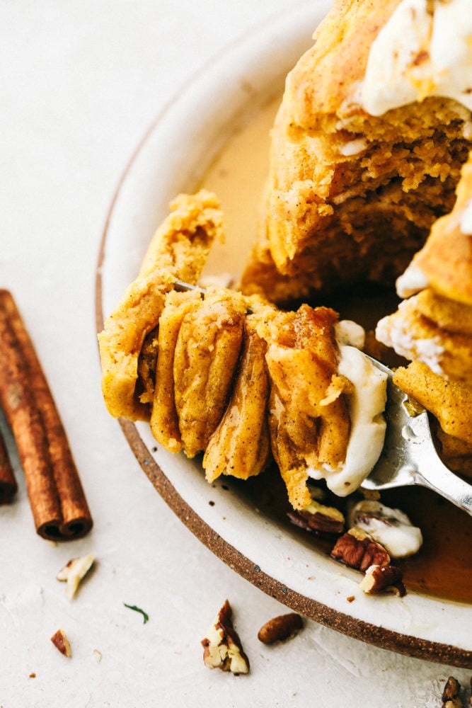 Top close view of a fork cutting into a stack of pumpkin spice pancakes.