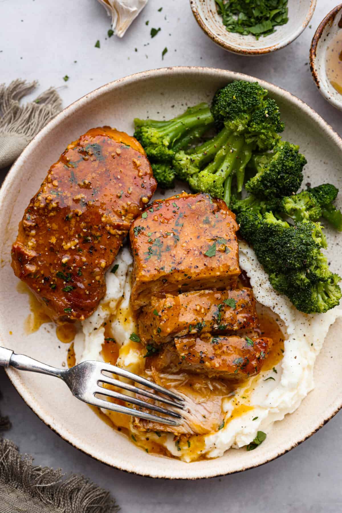 A sliced pork chop served with broccoli and mashed potatoes.