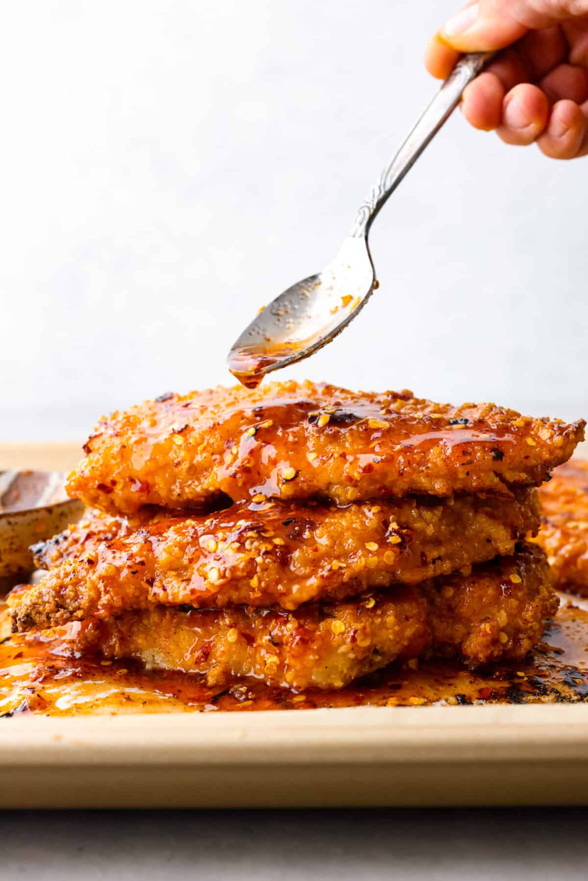 3 pieces of chicken stacked on top of each other, coated in a spicy glaze.