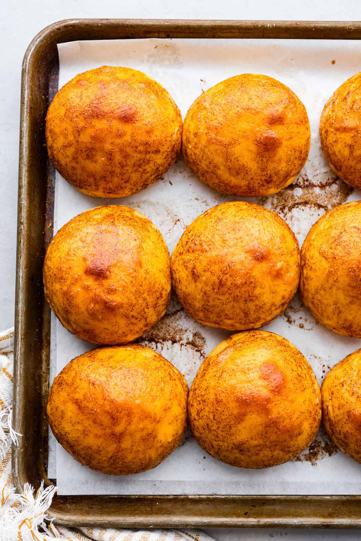 Top view of sweet potato rolls on a baking sheet pan brushed with brown sugar glaze.