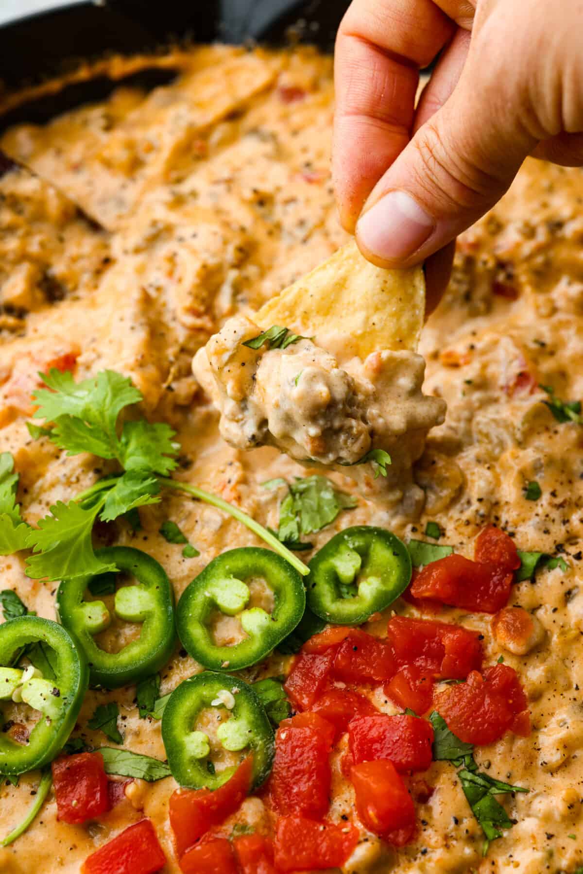 Dipping a tortilla chip into the cheesy dip.