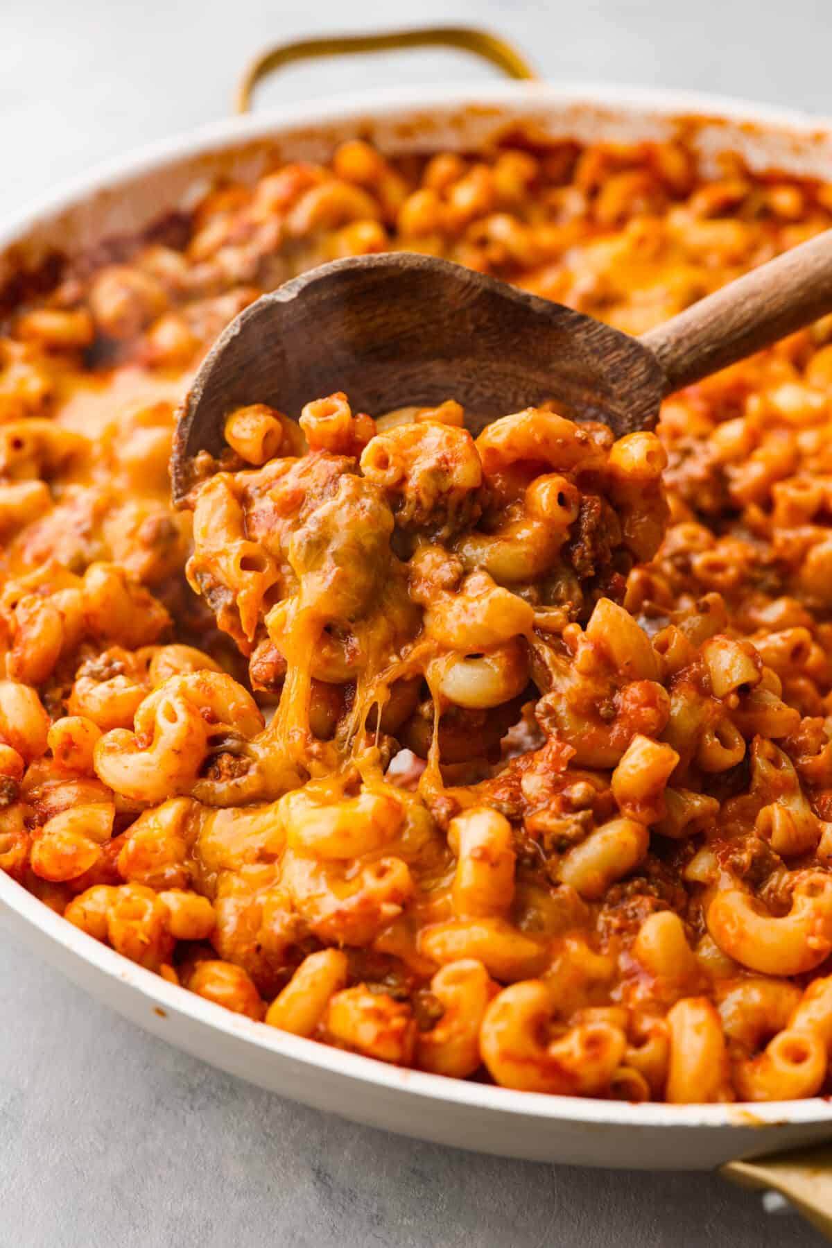 Closeup of a scoop of beefaroni in a wooden spoon.