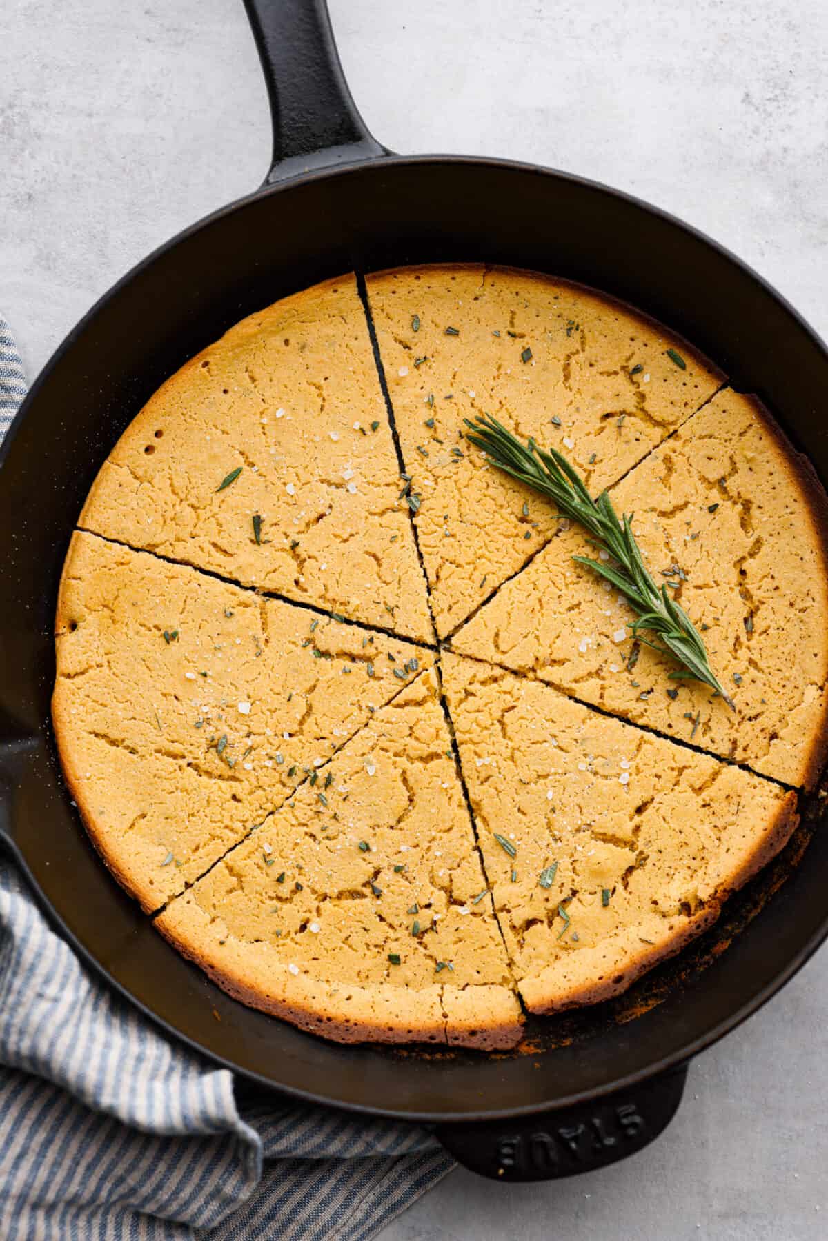 Top view of farinata in a cast iron skillet garnished with rosemary.