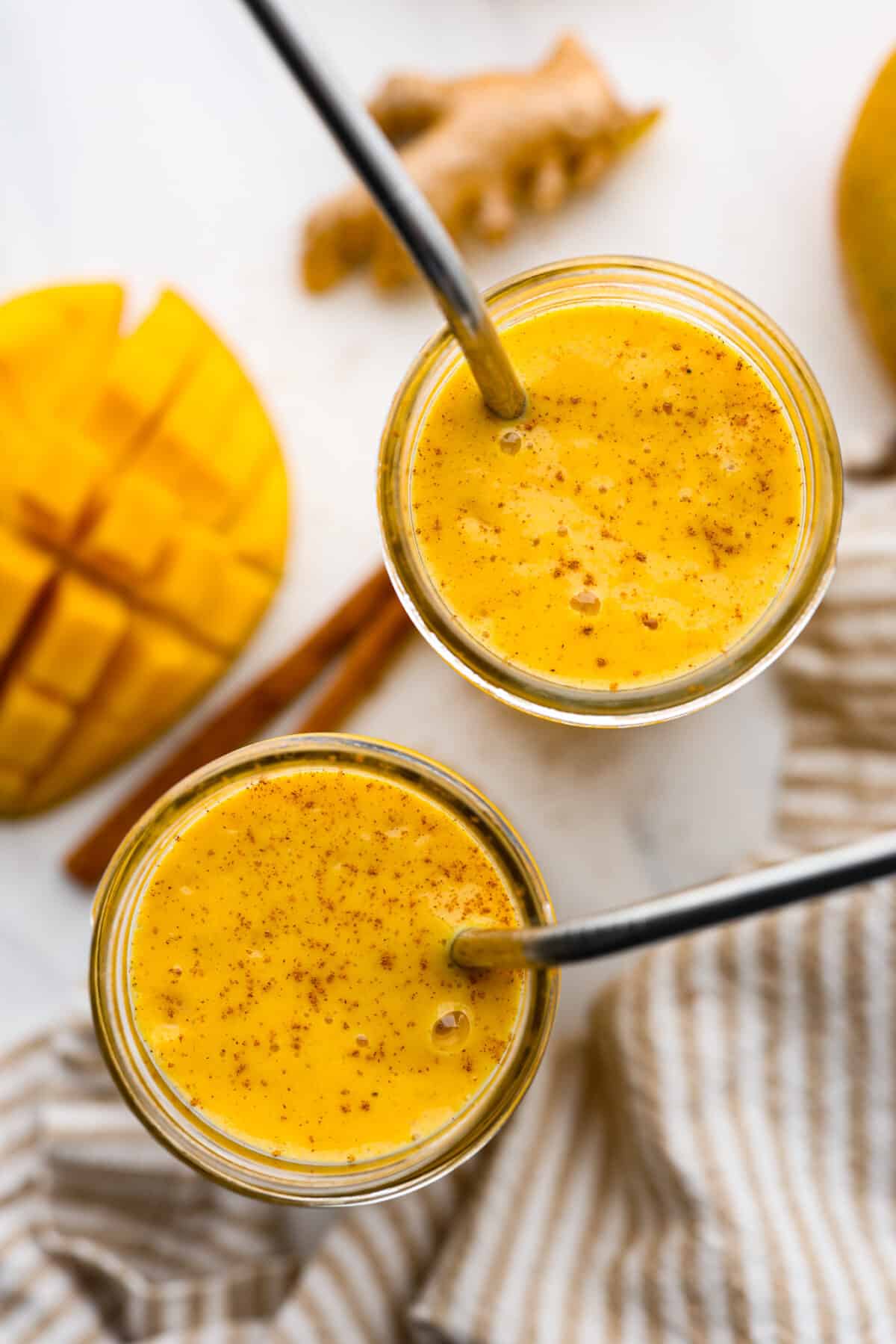 Top view of the smoothie in two glasses. Each glass has a metal straw and cinnamon garnished on top.