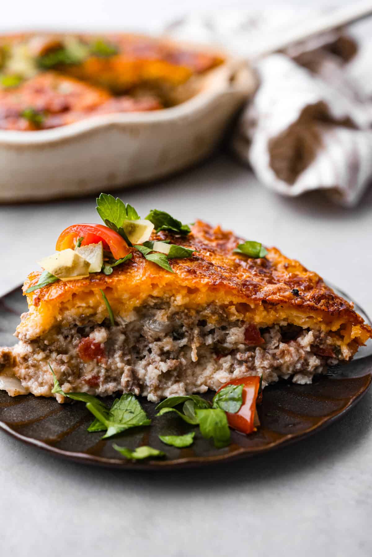 Close view of a slice of cheeseburger pie on a plate.