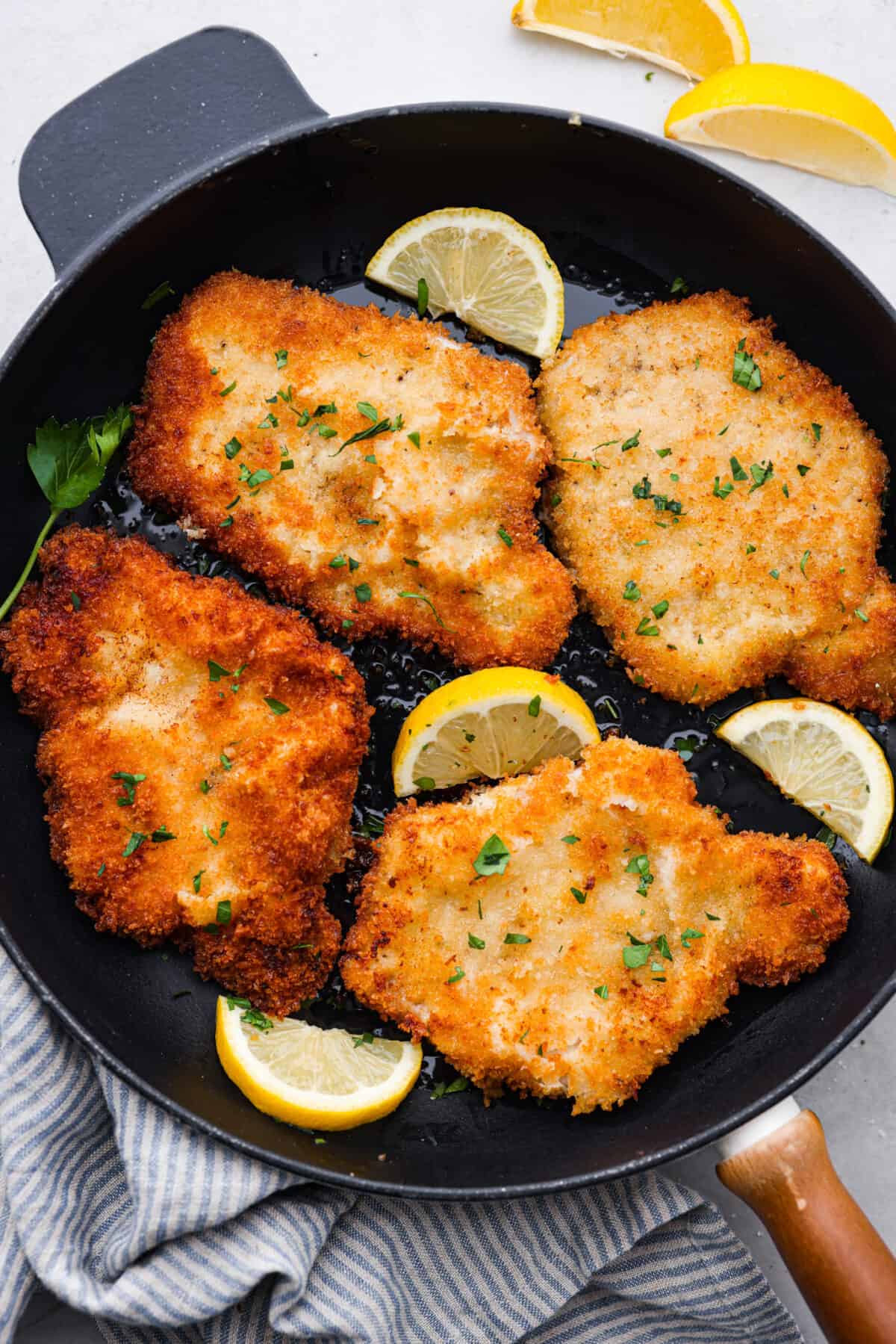 Cooked pork schnitzels in a black skillet.