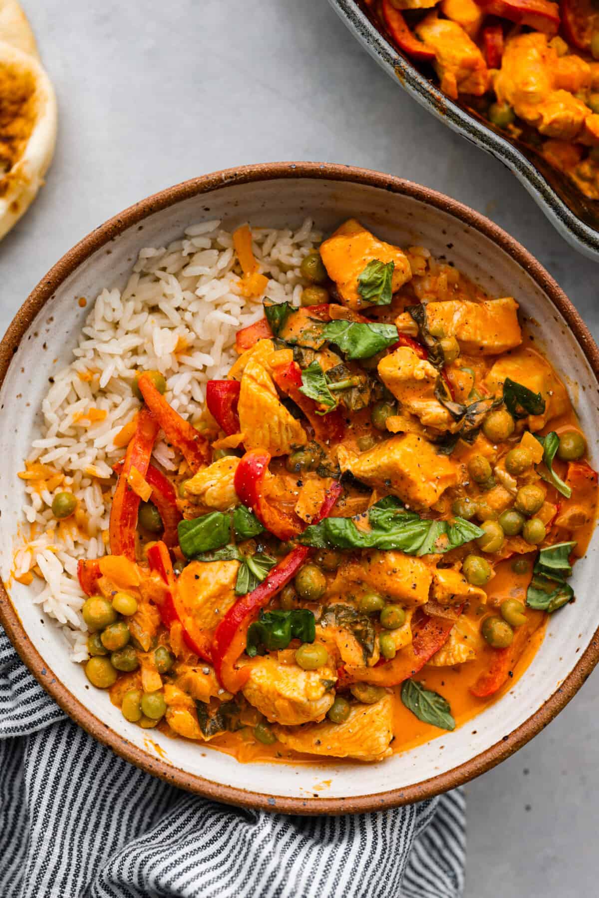 A serving of red curry and white rice in a stoneware bowl.