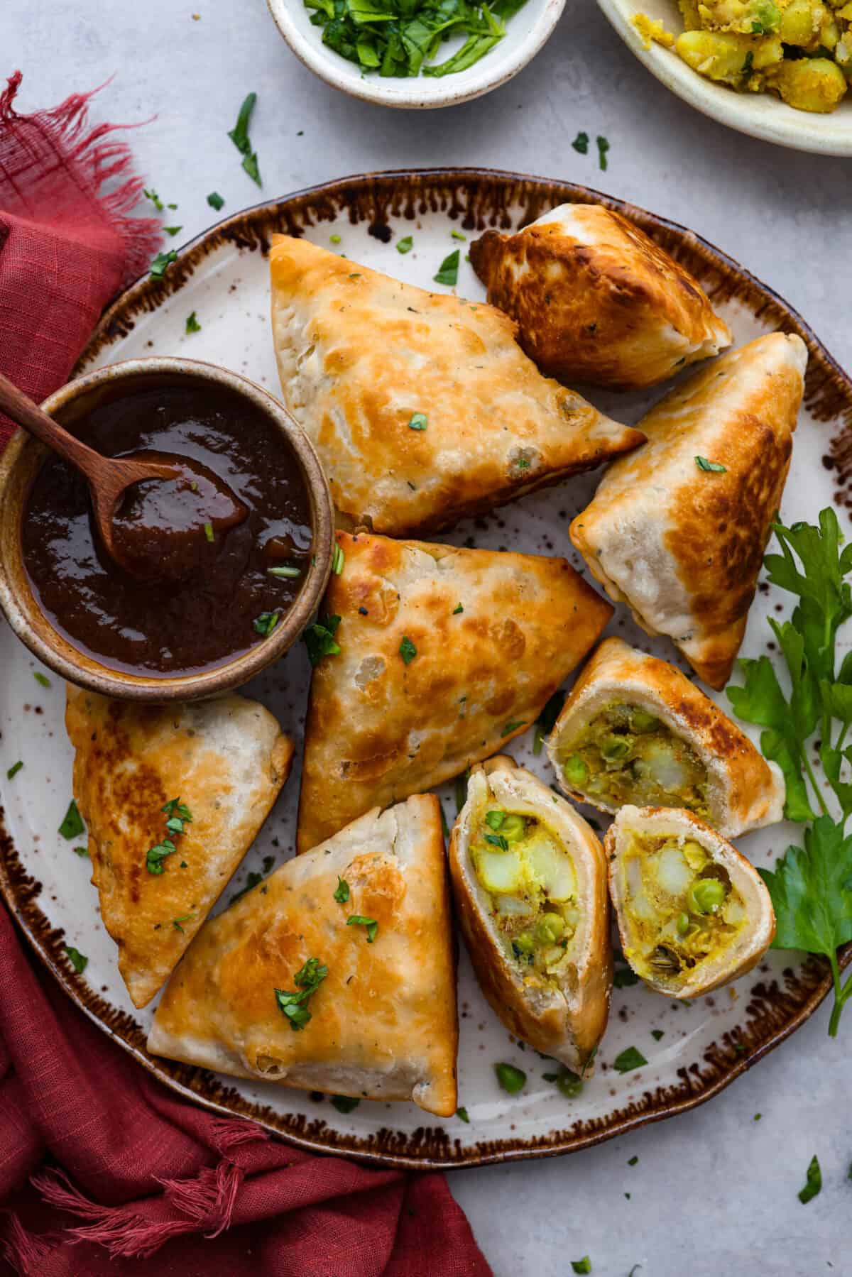 Samosas served on a plate alongside a thick red sauce.