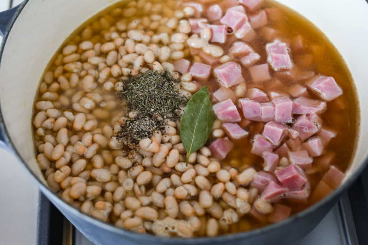 Fourth process photo of the bay leaf, pepper, and thyme added to the pot.