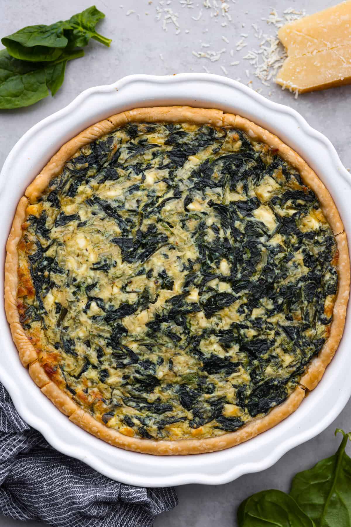 Top view of the baked spinach pie in a white pie dish.