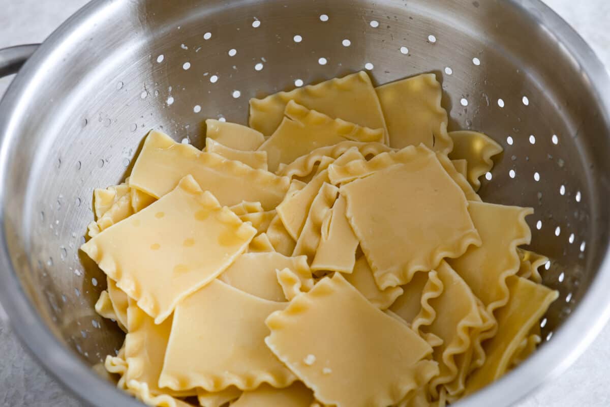 A strainer with lasagna noodles broken up. 