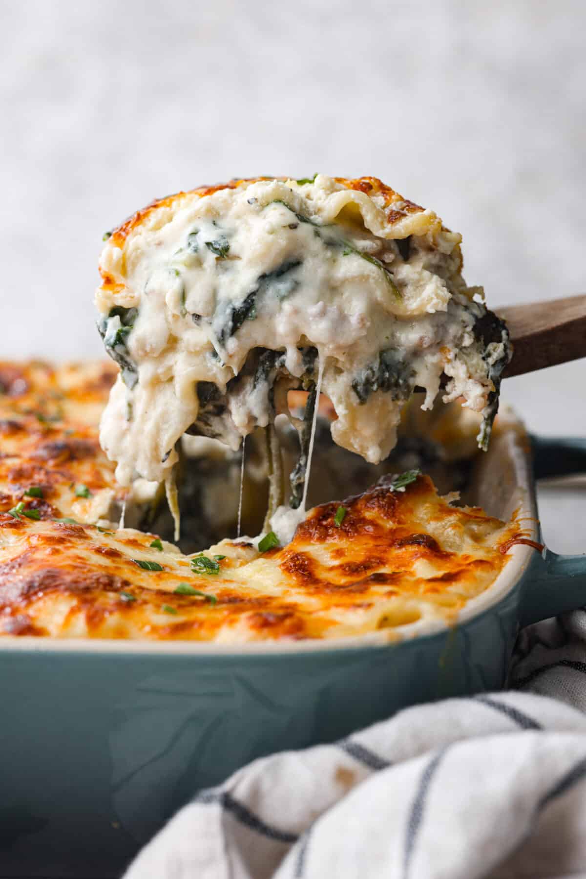 Scooping up lasagna with a wooden spoon.