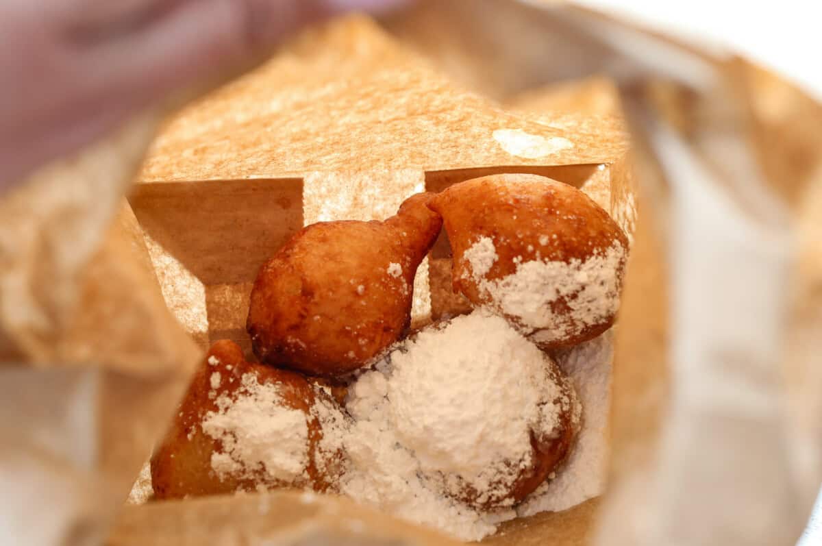 close up shot of zeppoles in paper bag with powdered sugar. 