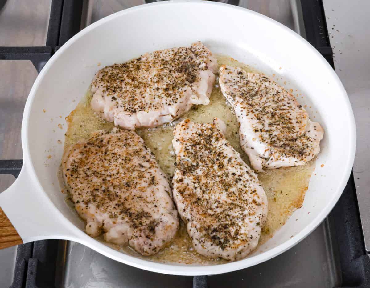 Angle shot of seasoned pork chops in pan. 