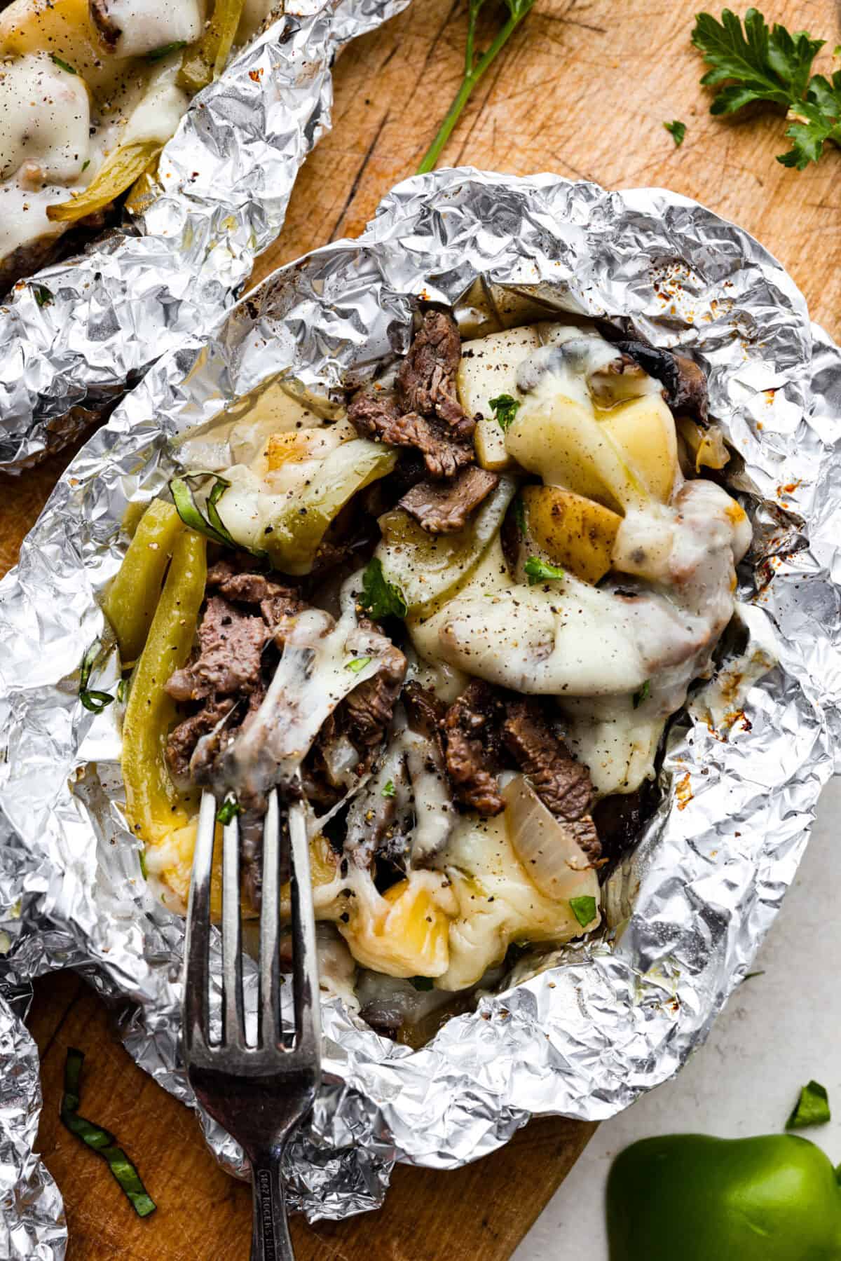 Over head shot of philly cheesesteak foil pack with fork. 